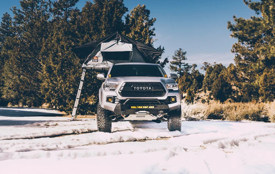 Overlanding vehicle with Body Armor 4x4 Sky Ridge Pike Rooftop Tent deployed in forest setting, adventure-ready rooftop camping setup