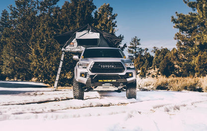 Overlanding vehicle with Body Armor 4x4 Sky Ridge Pike Rooftop Tent deployed in forest setting, adventure-ready rooftop camping setup