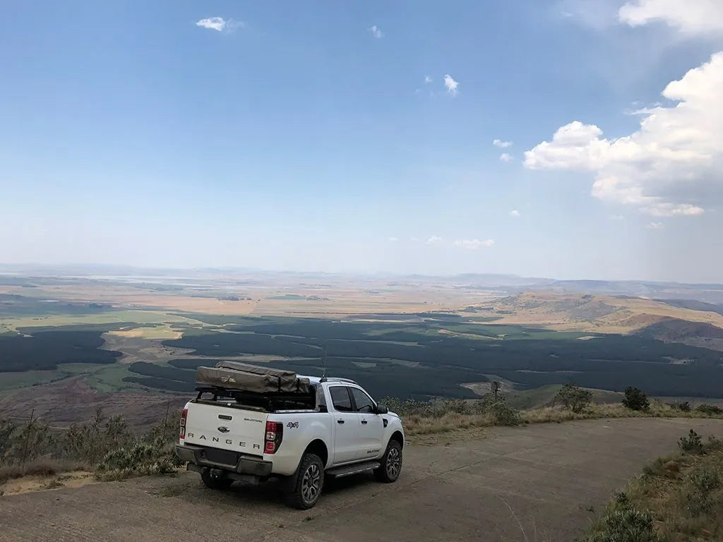 Ford pickup overlanding in mountain terrain with FrontRunner Slimline 2 Full Truck Bed Rack Kit and rooftop tent setup for rugged exploration