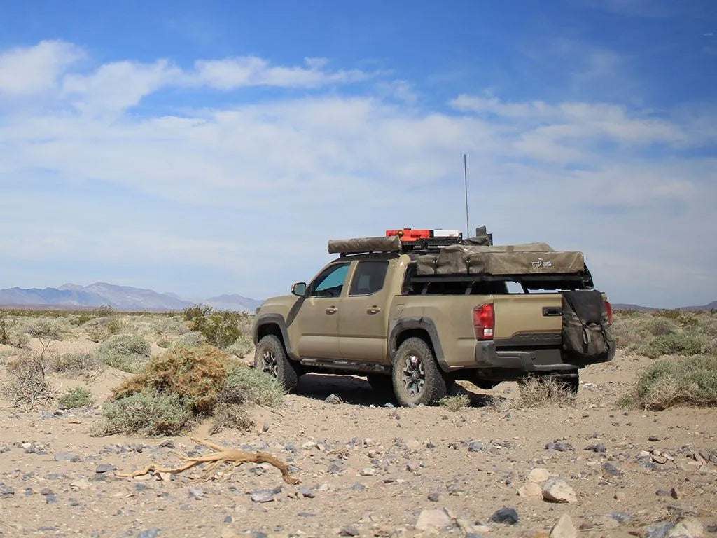 Toyota pickup with FrontRunner Slimline 2 Full Truck Bed Rack Kit overlanding in open landscape, rooftop tent-ready modular rack system in use