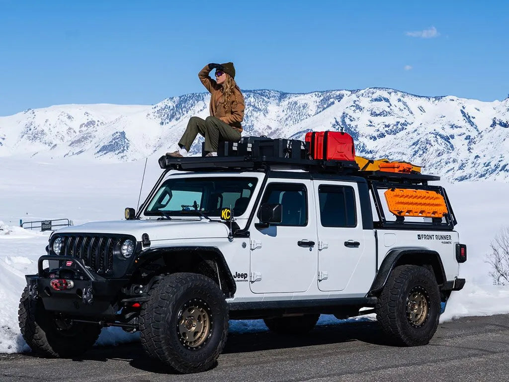 Jeep Gladiator overlanding in snowy mountains, equipped with FrontRunner Pro Bed Rack Kit and Slimline II Roof Rack carrying rooftop tent and adventure gear