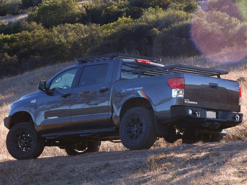 Toyota pickup off-roading at dusk with FrontRunner Slimline 2 Full Truck Bed Rack Kit and rooftop tent, rugged overlanding setup