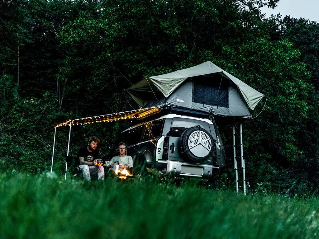 Land Rover overlanding campsite setup featuring vehicle with FrontRunner Slimline 2 rack and rooftop tent, full camp scene with gear
